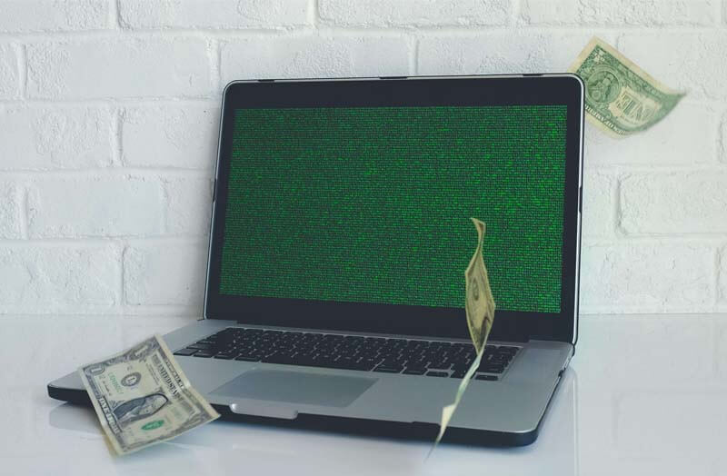 imagen de una laptop y 3 billetes alrededor